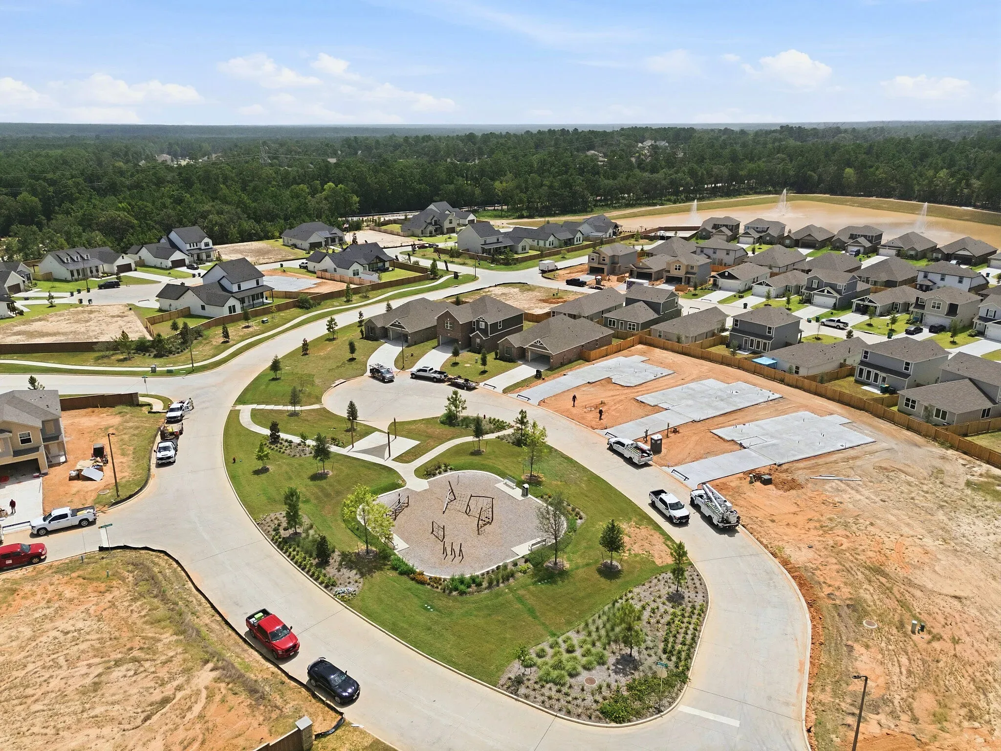 Aerial view of Magnolia Woods homes, neighborhood streets, playground, and pond in Magnolia, Texas