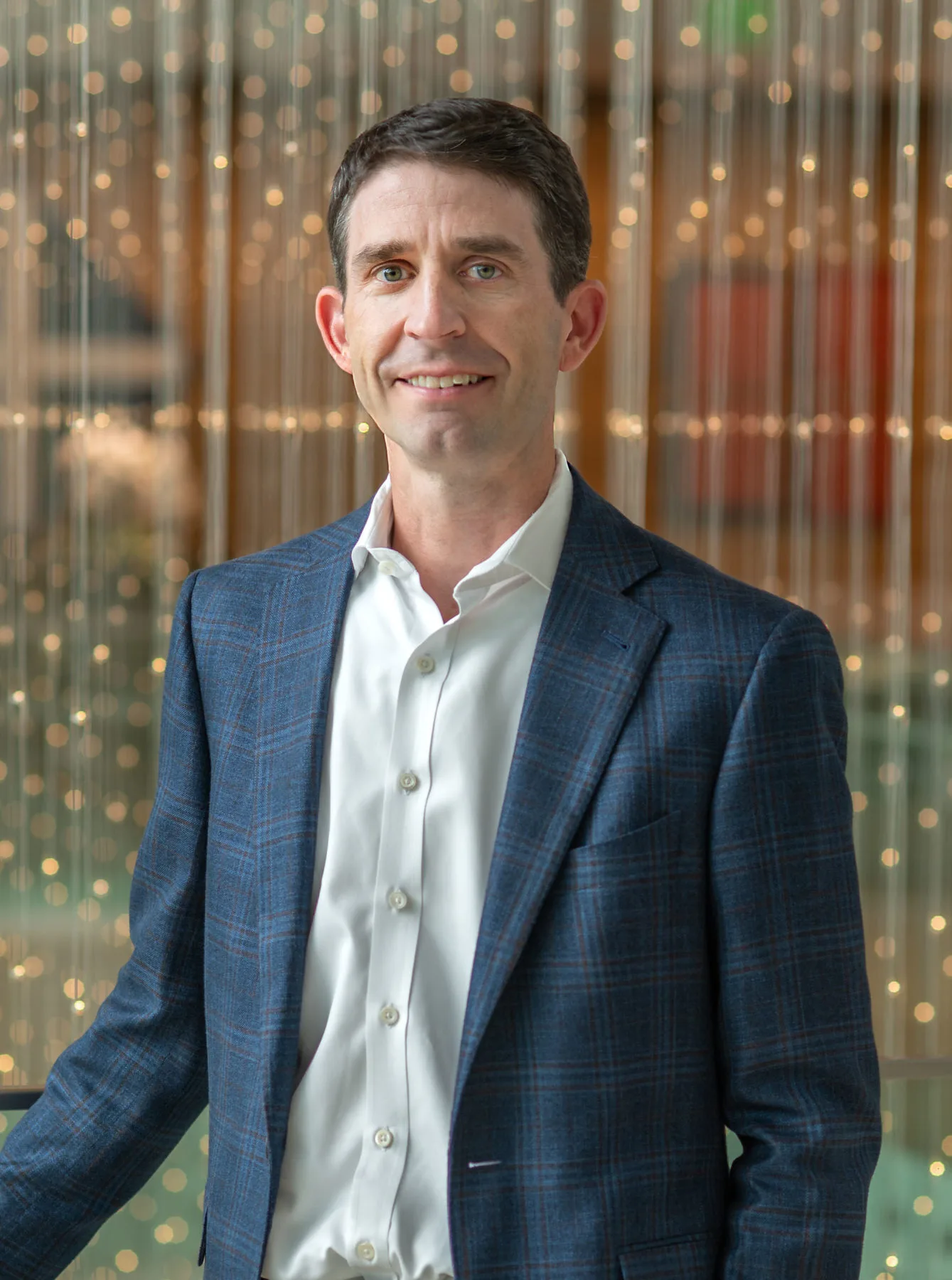 Man in business attire standing in front of blurred background with lights, representing Texas MUD financing and MUD distr...