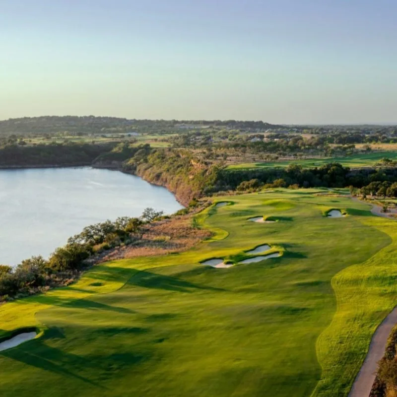 Aerial view of a serene Texas golf course with a lake, showcasing MUD district funding solutions and Texas MUD financing o...