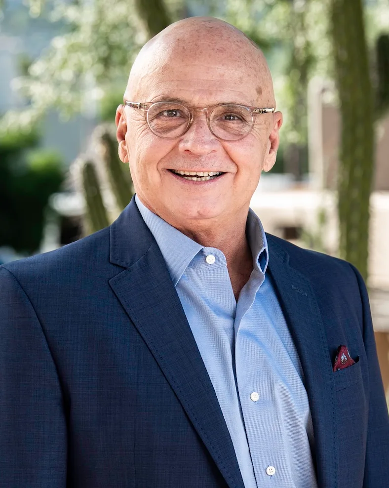 Bald man in blue suit and glasses smiling outdoors, representing expertise in Texas MUD financing and MUD district funding...